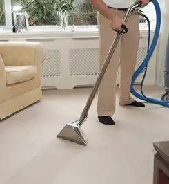 Professional carpet cleaner using a hot-water extraction wand and hose machine in a living room in Tempe, AZ.