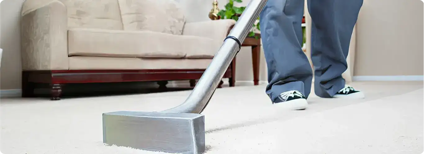 Carpet cleaning technician using a hot-water extraction wand on a light-colored carpet in a living room, Tempe, AZ.