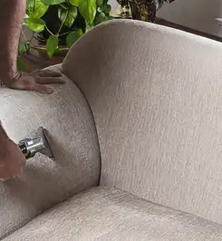 Professional upholstery cleaner deep-cleaning a fabric sofa with a handheld extraction tool and hose Tempe, AZ.